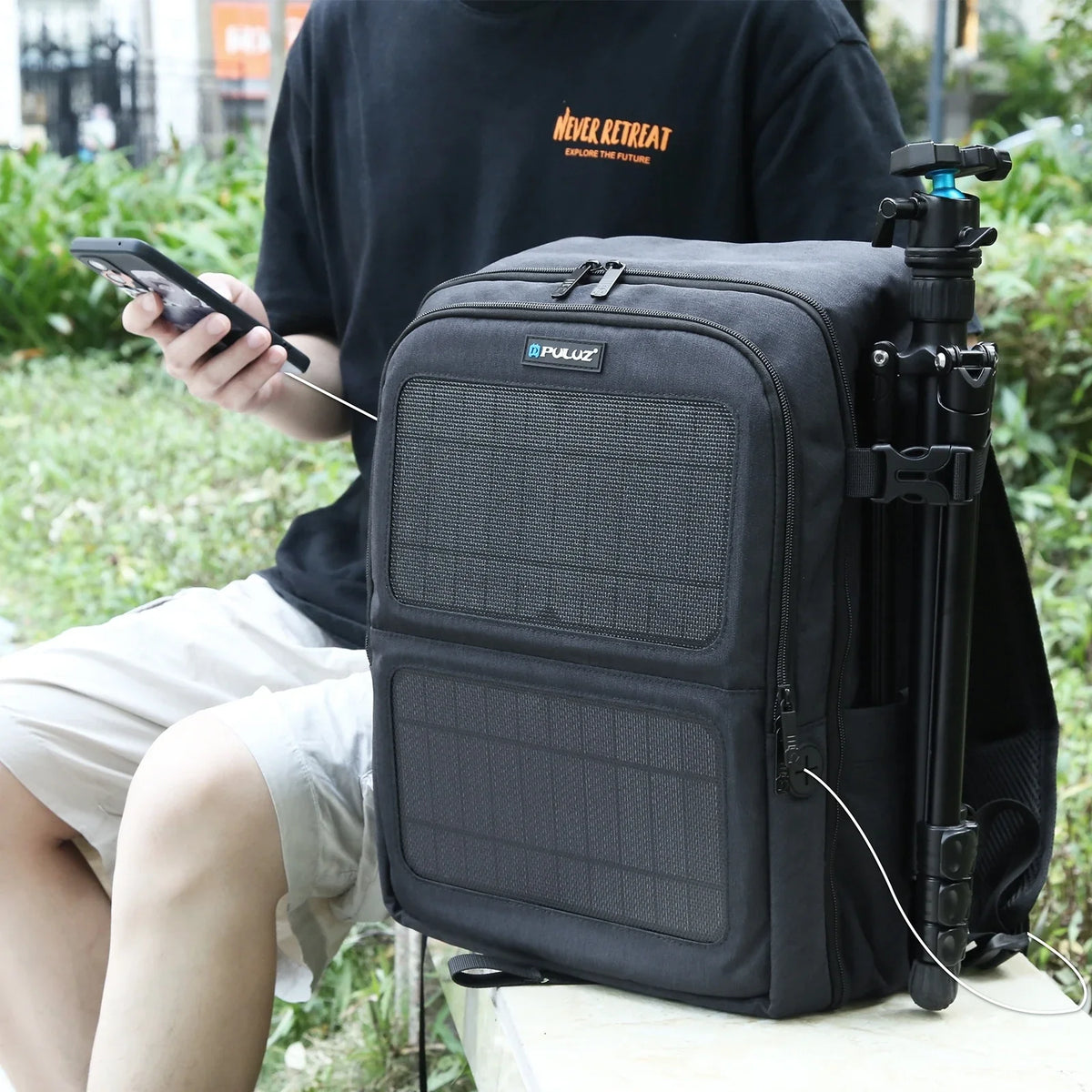 Portable solar backpack charging phone outdoors, tripod attached, ideal for adventurers